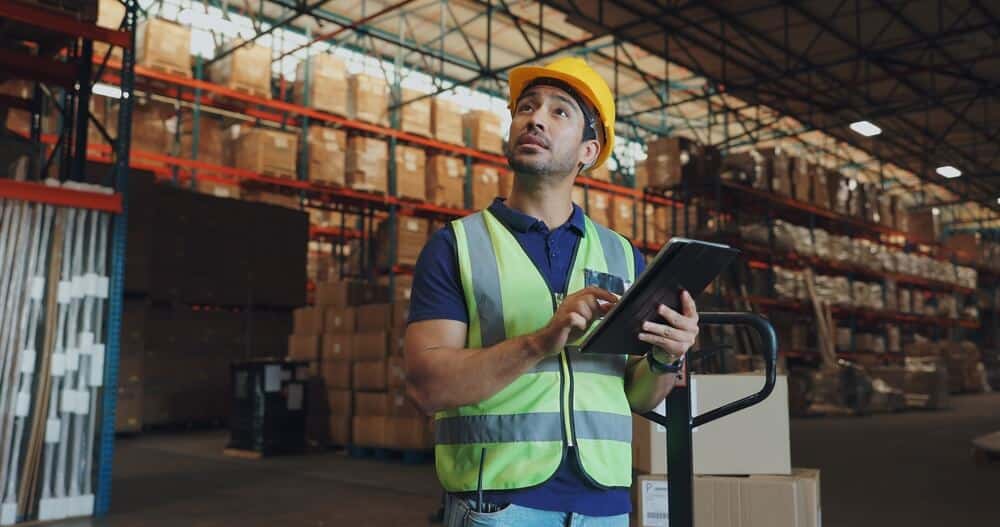 Man in a warehouse using technology as part of the supply chain.