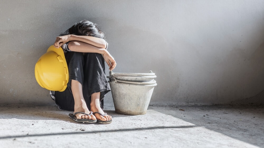 Child in corner crying because she is being forced to work.