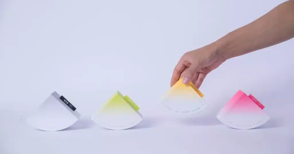 Modern color-gradient product packaging displayed in a row with a hand selecting one, illustrating unique product development and product innovation in consumer goods.